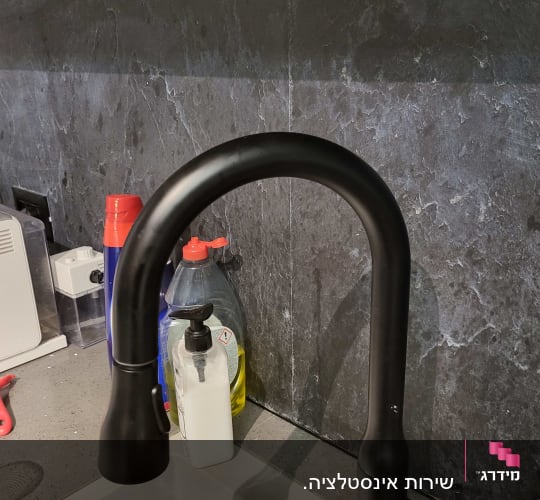 ברז שחור בכיור עם חומרי ניקוי מסביב